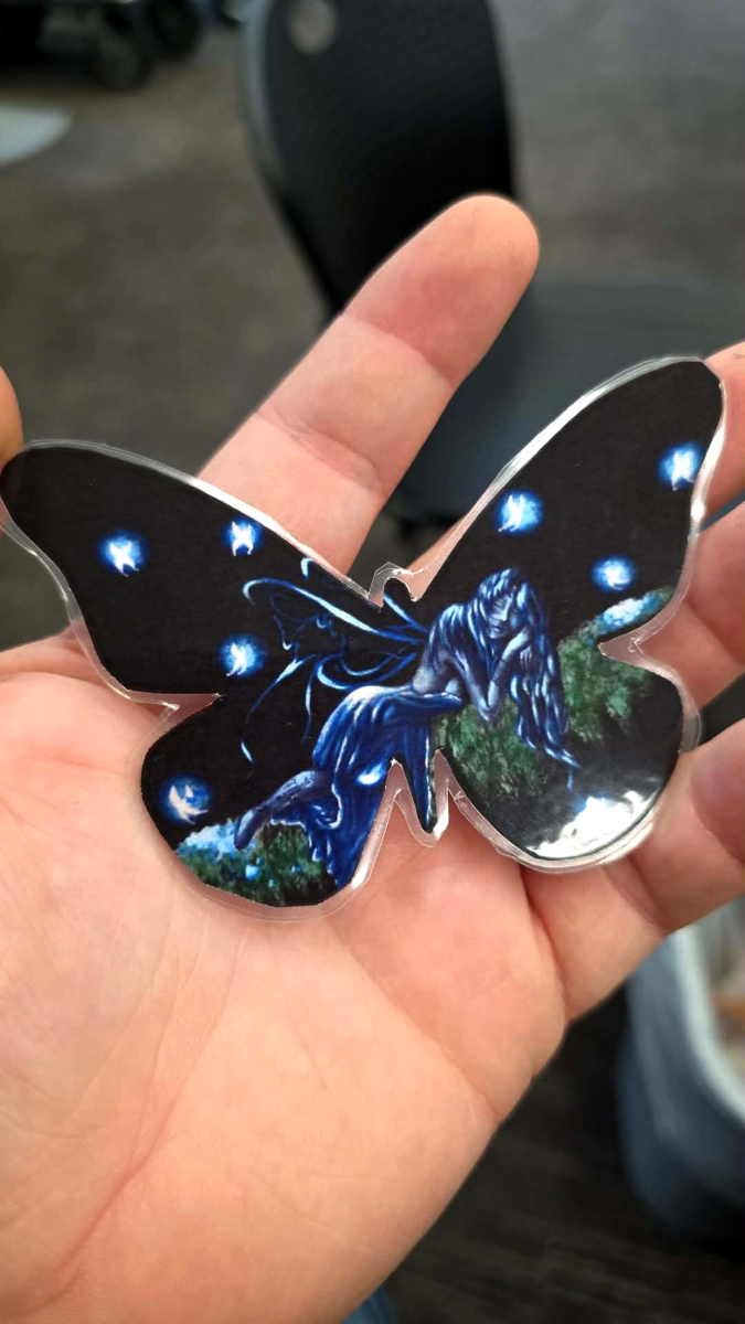 Black butterfly-shaped die-cut print with blue and white highlights held in a hand